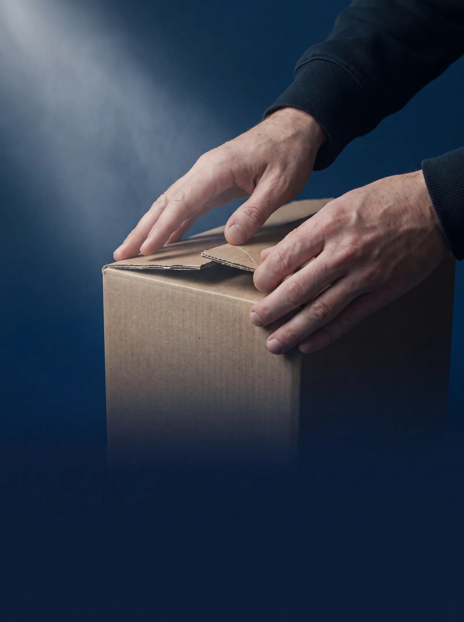 Hände schließen einen unbedruckten Versandkarton aus Recyclingpappe